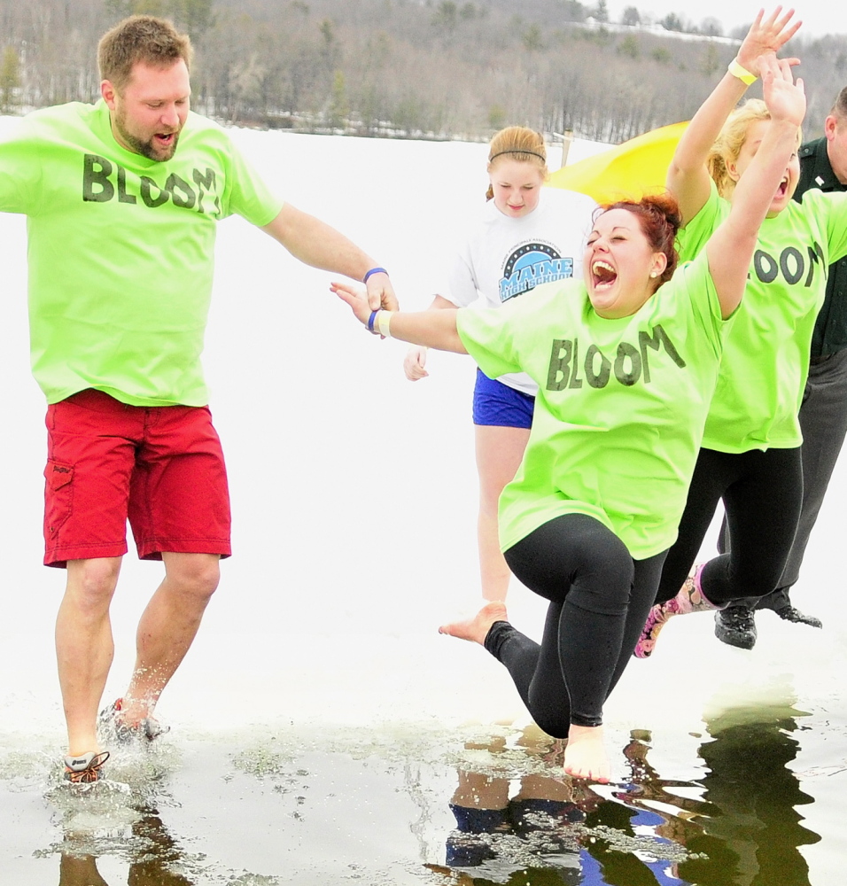 Green-shirted Team Bloom members Corey Rubchinuk, left, Kayla Diplock and Kim Stoenton leap into Maranacook Lake during the Ice Out Plunge on Saturday in Winthrop.