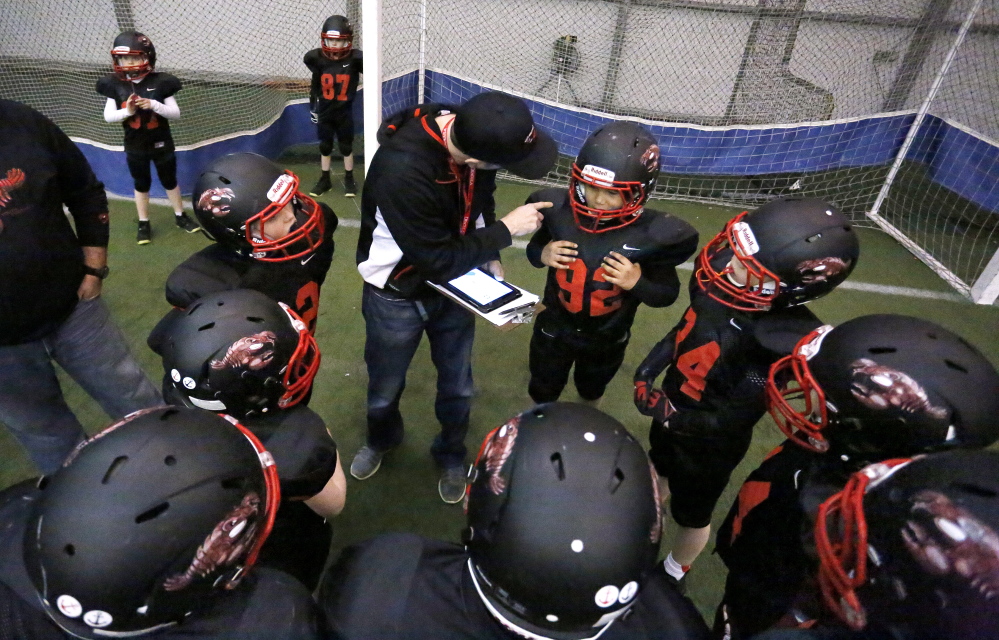 Head coach Skip Winter, center, talks to Mark Erinna, at right, and other Seacoast Lobsters players during a winter practice in York. The youth team’s eight coaches teach heads-up tackling to try to prevent concussions.