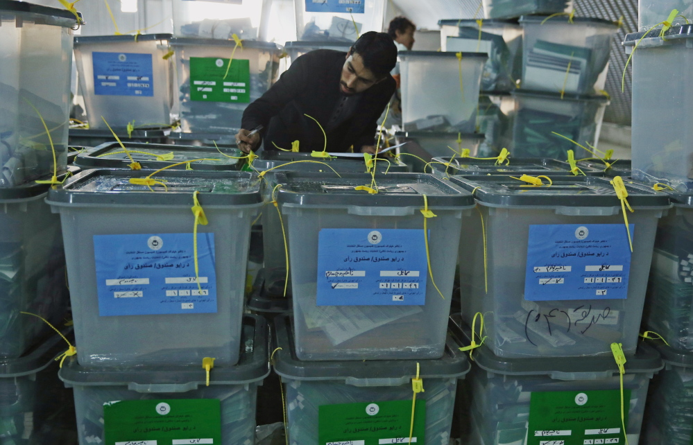 An Afghan elections worker notes serial numbers on ballot boxes at an official elections warehouse in Kabul, Afghanistan on Sunday, as trucks and donkeys loaded with ballot boxes made their way to counting centers.