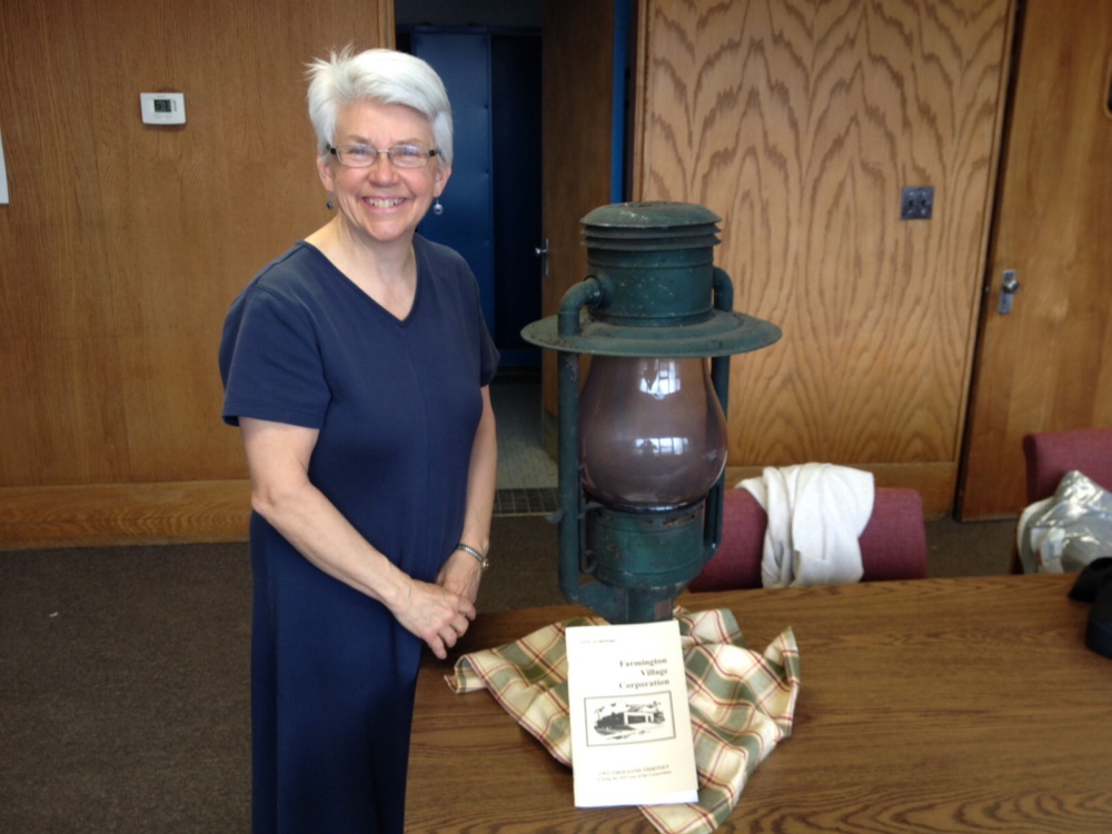 Jane Woodman, business manager for the Farmington Village Corporation, stands next to a 130-year-old lamp that came from an era when the corporation, not the town, ran the municipal streetlights.