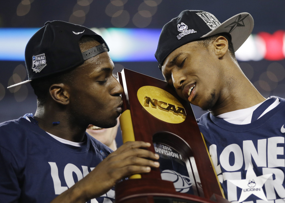 Connecticut guard Terrence Samuel, left, and guard Lasan Kromah hold the championship trophy after beating Kentucky 60-54, at the NCAA Final Four championship game on Monday in Arlington, Texas.