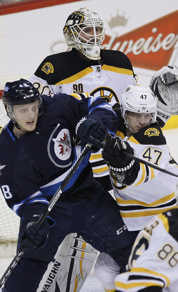 Boston’s Torey Krug tries to clear Winnipeg’s Carl Klingberg from in front of goaltender Chad Johnson during Thursday’s game in Winnipeg, won by the Jets.