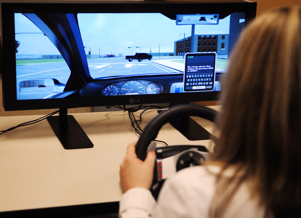 Winthrop High School freshman Kayleigh Oberg demonstrates a distracted driving simulator after a news conference about distracted driving Thursday in Augusta.