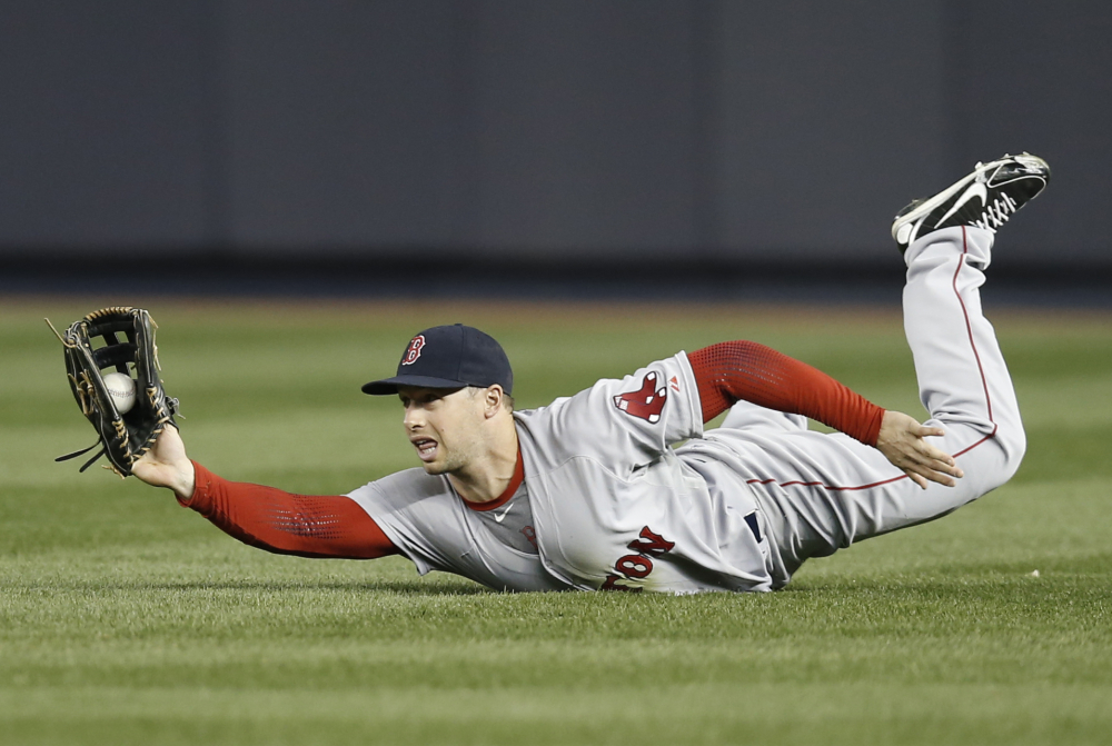 Boston Red Sox right fielder Daniel Nava shows the ball to the umpire after making a sliding catch on a third-inning fly-out hit by Yankees third baseman Yangervis Solarte.