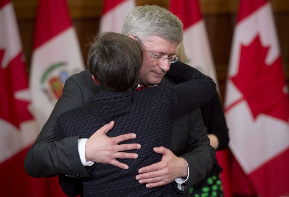Canadian Prime Minister Stephen Harper embraces MP Kellie Leitch after announcing that former Finance Minister Jim Flaherty had died Thursday in Ottawa. Harper called the death of the long-serving minister “an unexpected and a terrible shock.”