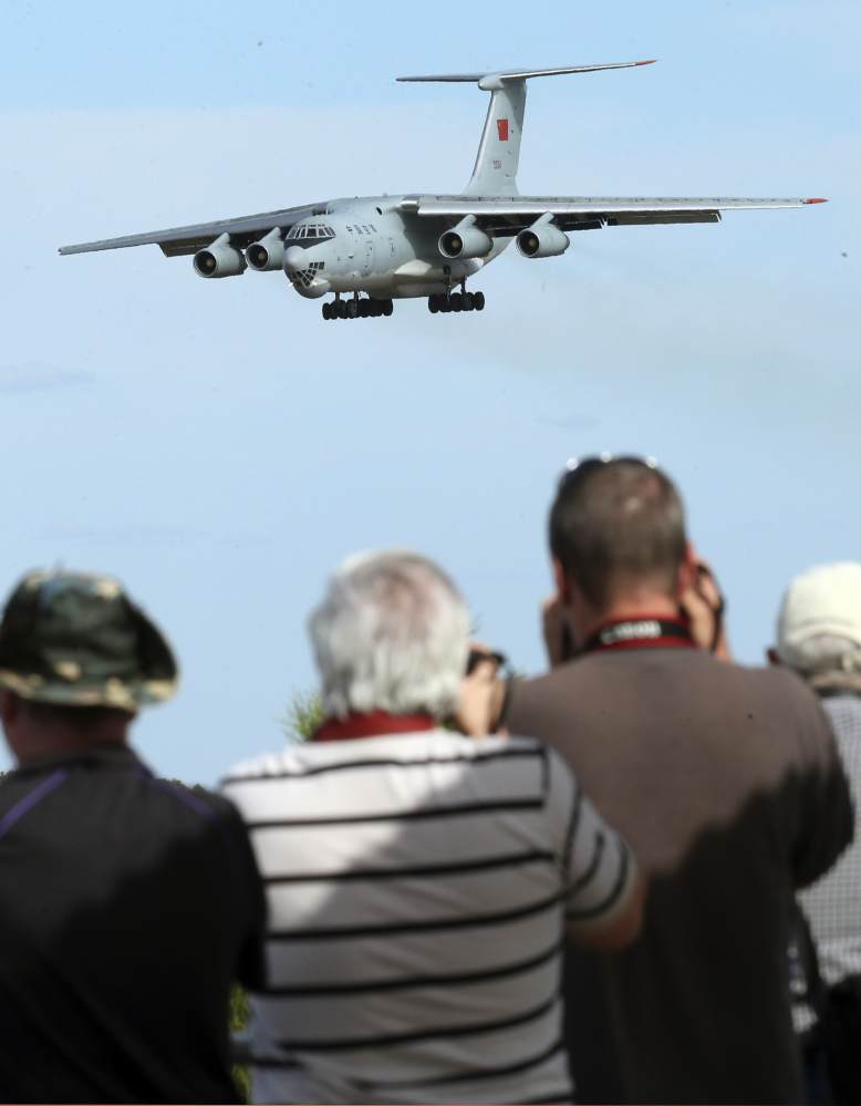Spectators take photos of a Chinese Ilyushin IL-76 aircraft as it comes in for a landing at Perth International Airport after returning Thursday from the ongoing search operations for missing Malaysia Airlines Flight 370.