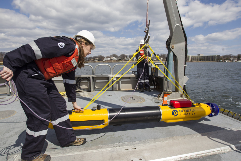A submarine built by Bluefin Robotics is prepared by systems engineer Cheryl Mierzwa to be deployed into the water in Quincy, Mass., on Wednesday. Bluefin Robotics shipped a version of their submarine to help locate missing Malaysian Airlines Flight 370.