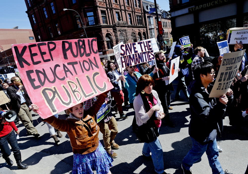 Marchers protesting USM budget cuts carry signs down Middle Street in Portland on Thursday.