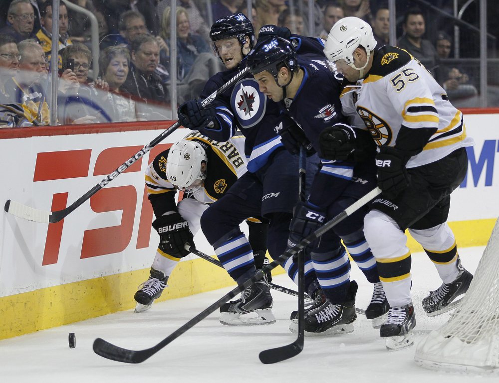 Boston Bruins’ Matt Bartkowski and Johnny Boychuk (55) scramble with Winnipeg Jets’ Carl Klingberg, center left, and Patrice Cormier for the puck behind the Bruins’ net during the second period Thursday.