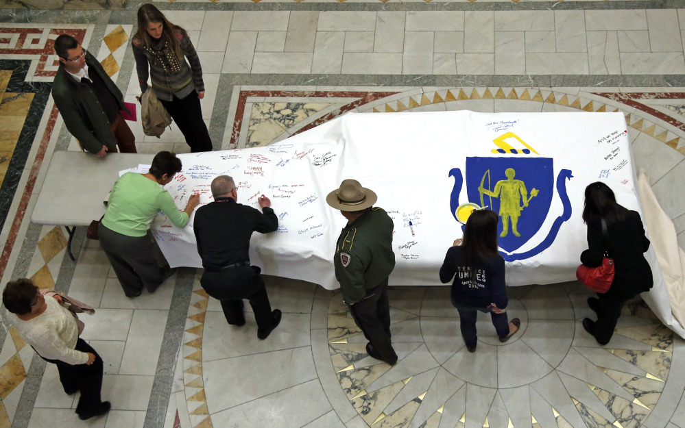 People sign the America 4 Boston Prayer Canvas at the Statehouse in Boston in memory of marathon bombing victims.