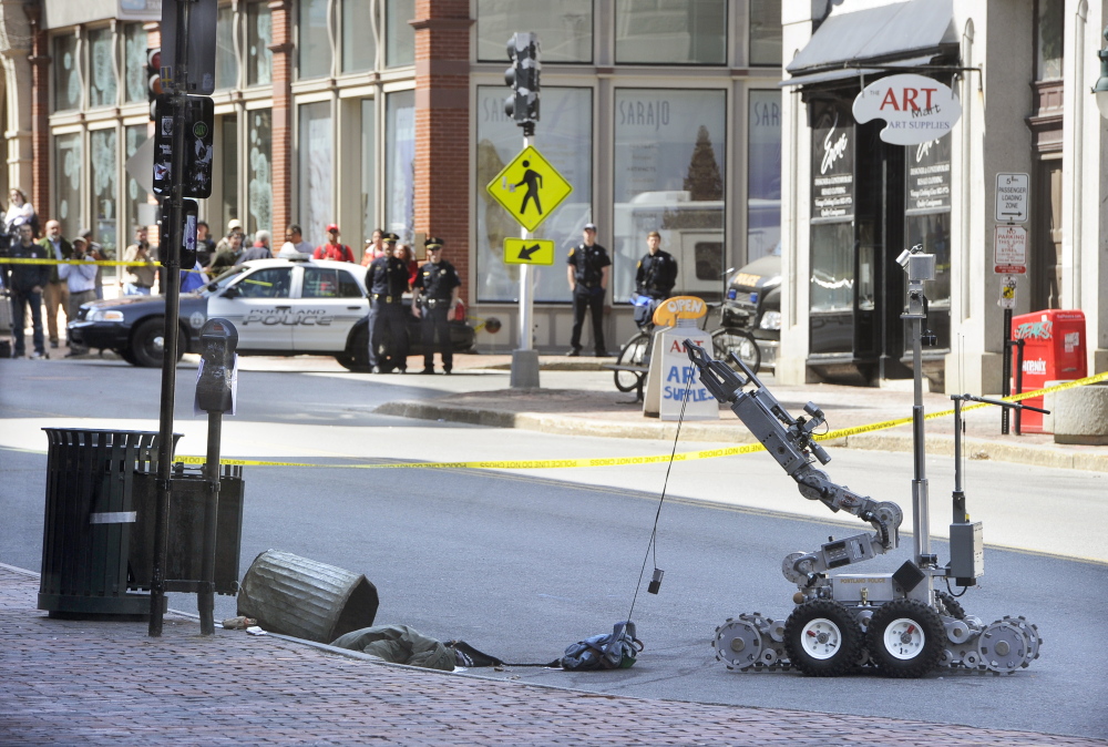 A Portland police bomb squad robot retrieves a device used in a robbery Friday morning from a trash can at the CVS drugstore at 510 Congress St.