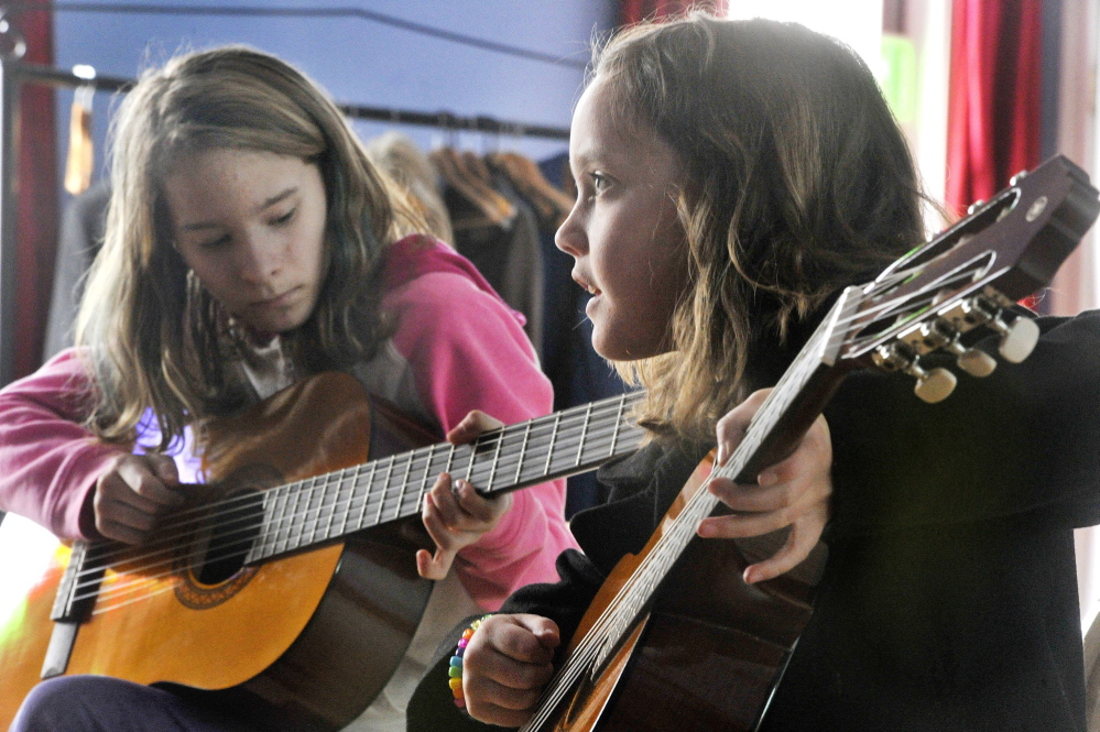 Guitar students Maya DeSouza, left, and Aoife Mahoney practice during a recent lesson at Mayo Street Arts.