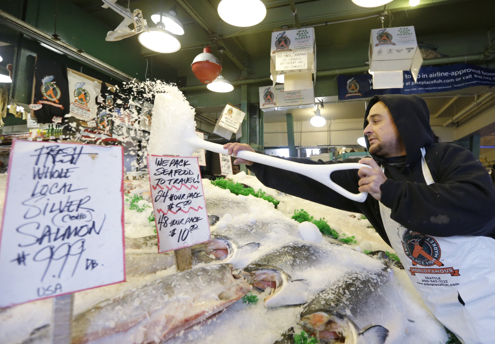 Fishmonger Erik Espinoza shovels ice onto fresh fish at the Pike Place Market in Seattle. Lawmakers in both state legislatures and in Washington, D.C., have been considering bills to help to ensure more accurate labeling of seafood.