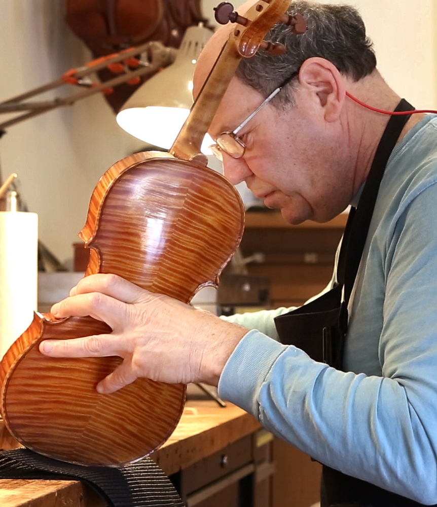 In his Portland workshop, Jonathan Cooper repairs an instrument owned by violinist Mark O’Connor.