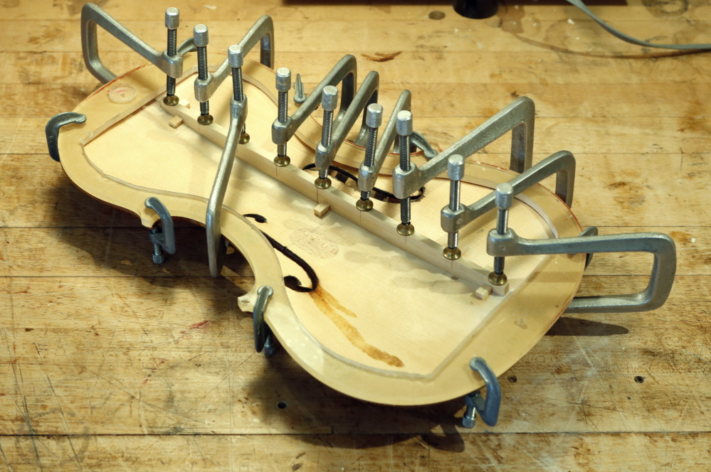 Clamps hold a bass bar in place while the glue holding it in place dries on a bench in the Artistic Artisans workshop in Portland Thursday. Jonathan Cooper, owner of Artistic Artisans, made the violin in 2002 and was repairing it for Mark O’Connor after the violin was damaged.