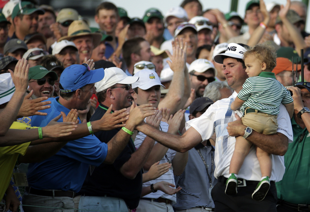 Bubba Watson, carrying his son Caleb, is congratulated by spectators after winning the Masters golf tournament Sunday in Augusta, Ga.