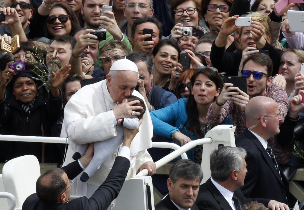 Pope Francis kisses a baby at the close of the Palm Sunday Mass in St. Peter’s Square at the Vatican on Sunday.