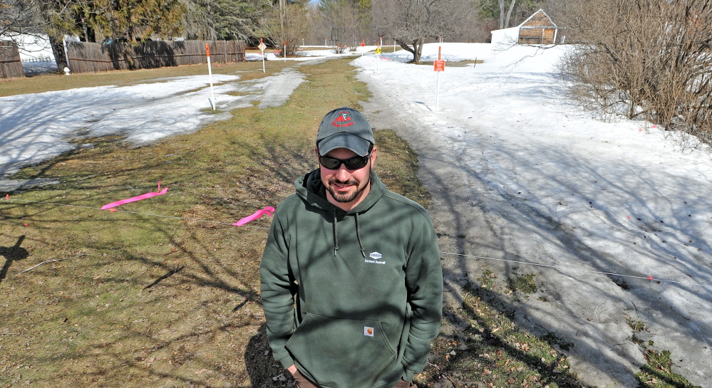 Todd Dixon, president of Solon Snow Hawks, stands by a snowmobile trail that crosses U.S. Route 201 in Solon on Saturday.