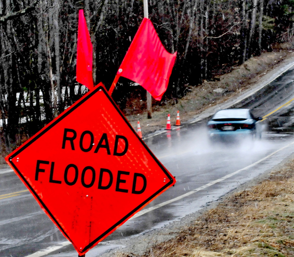 A motorist drives through water that collected on Middle Road in Skowhegan just past warning signs on a wet Sunday. The National Weather Service has issued a flood watch for many parts of the state, including Kennebec, Somerset, Franklin and Waldo counties through Wednesday evening.