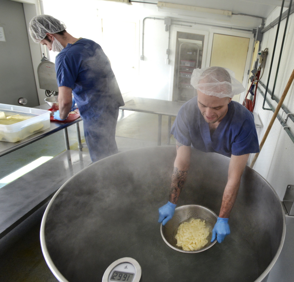 At top, cheese-maker Tyler Renaud breaks up curds and Kris Burleigh soaks them in steaming water at Silver Moon Creamery in Westbrook.