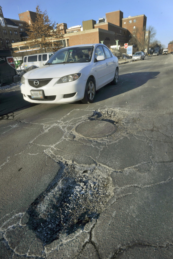 PORTLAND, ME - FEBRUARY 28: The city of Portland has issued a pothole warning and asks drivers to watch out for repair crews and to report potholes. A car drives around a pair of large potholes on Bramhall Street, near Maine Medical Center. Friday, February 28, 2014. (Photo by John Ewing/Staff Photographer)