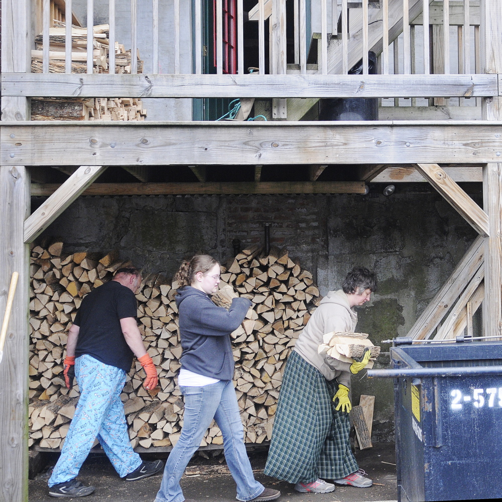 Donald Hallett, his daughter, Cassandra, and wife, Suzette, carry kiln-dried firewood Tuesday up to the first floor deck of Kennebec Pizza ahead of high water expected to come up over the banks of the Kennebec River. Kennebec Pizza stores the firewood for its ovens beneath the building on the shores of the river.