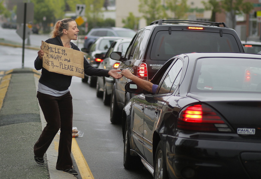 Alison Prior, 29, of Portland, receives change from a driver while she panhandles at the corner of Preble Street and Marginal Way last May. The city of Portland says panhandling interferes with public safety.