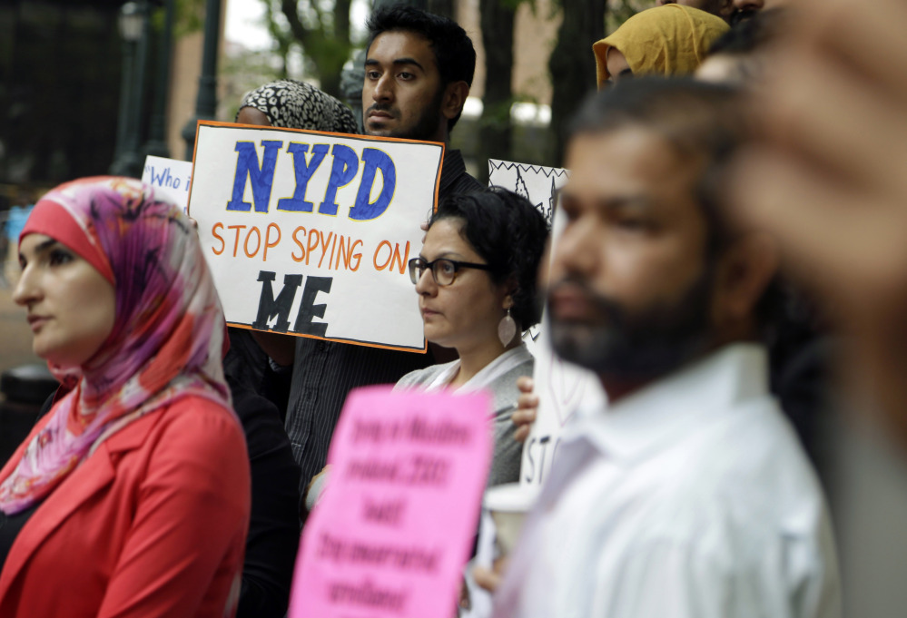 A group of people hold signs protesting the New York Police Department’s program of infiltrating and informing on Muslim communities during a rally near police headquarters in New York in August. The department announced Tuesday that the unit has been disbanded.