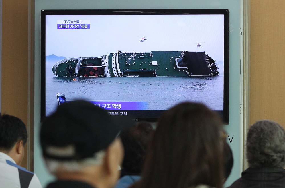 People at the Seoul Railway Station watch a TV news program showing the sinking ship Wednesday.