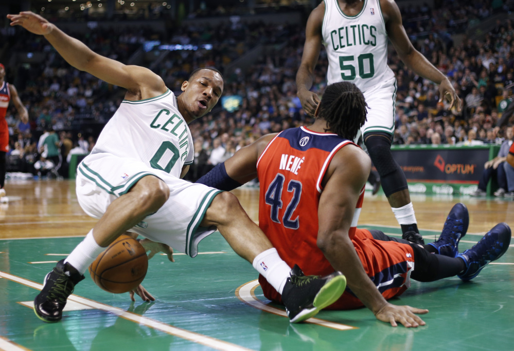 Boston Celtics guard Avery Bradley (0) loses his footing during a scramble for the ball with Washington Wizards forward Nene Hilario (42) during the first quarter of an NBA basketball game in Boston, Wednesday, April 16, 2014.