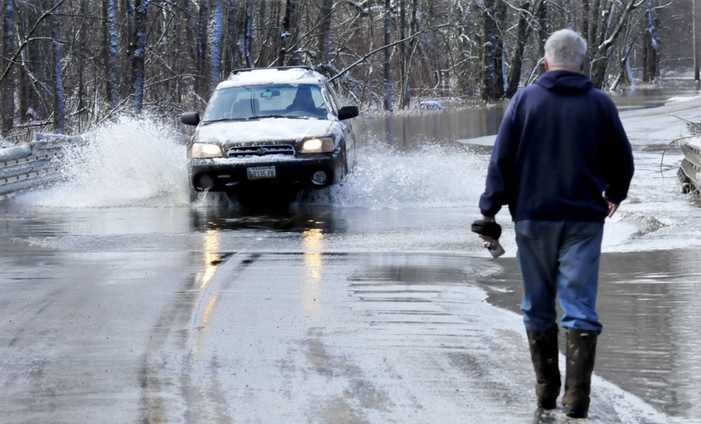 Bob Hueston stops to photograph cars passing through the 6 inches of water that flowed over Prairie Road in Unity on Wednesday. High water from nearby Twenty-five Mile Stream flooded the roadway but cars were able to get through.