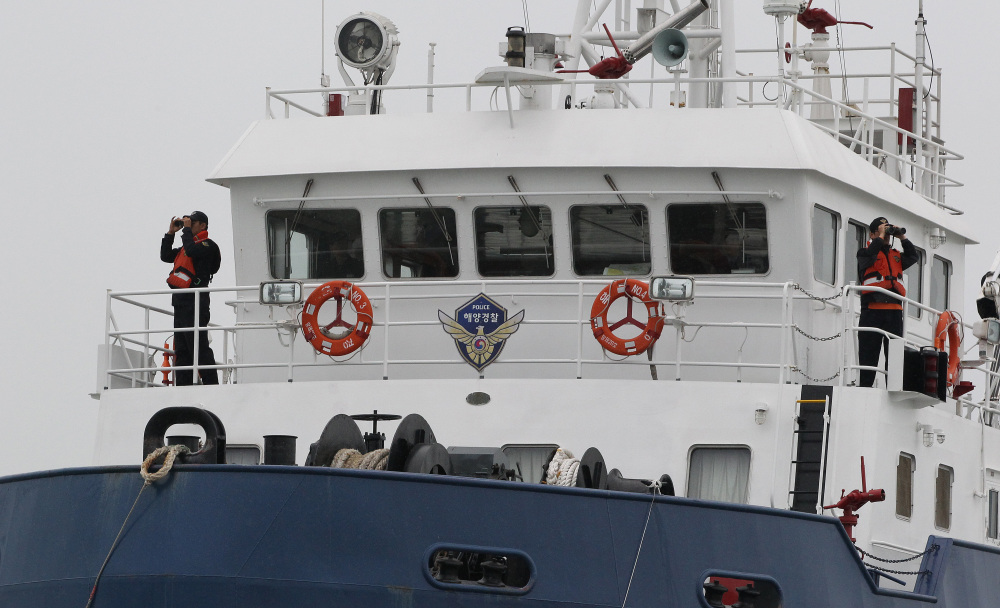 South Korean Coast Guard officers uses binoculars in search for missing passengers aboard their sunken ferry in the water off the southern coast near Jindo, South Korea.