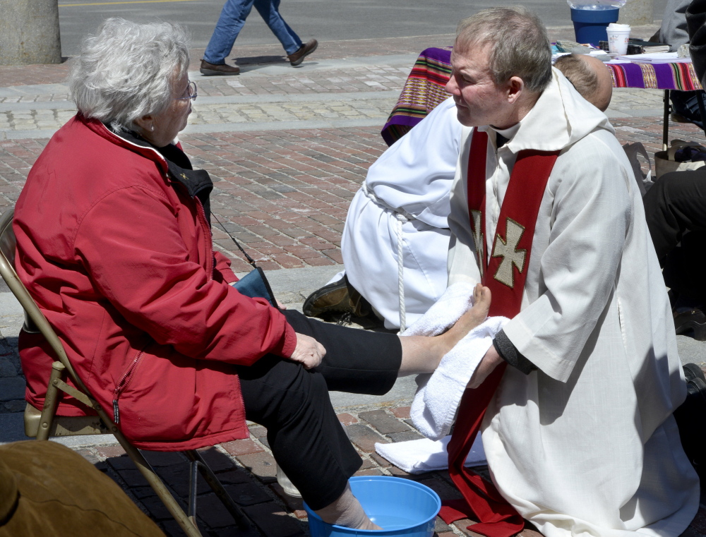 Sister Dale Jarvis of Portland, with the Sisters of Mercy, gets her feet washed by the Rev. Tim Higgins from St. Ann’s Episcopal Church in Windham during a Holy Thursday foot washing by clergy from area churches at Monument Square in Portland.
