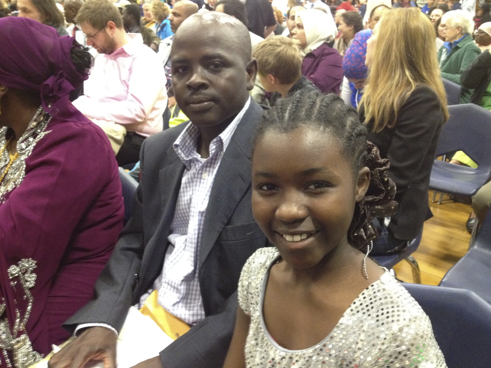 Sara Ali, 11, right, a student at Lyman Moore Middle School and an immigrant from Sudan, gets to see her uncle Abdelrazig Abdelshafie sworn in as a new U.S. citizen.