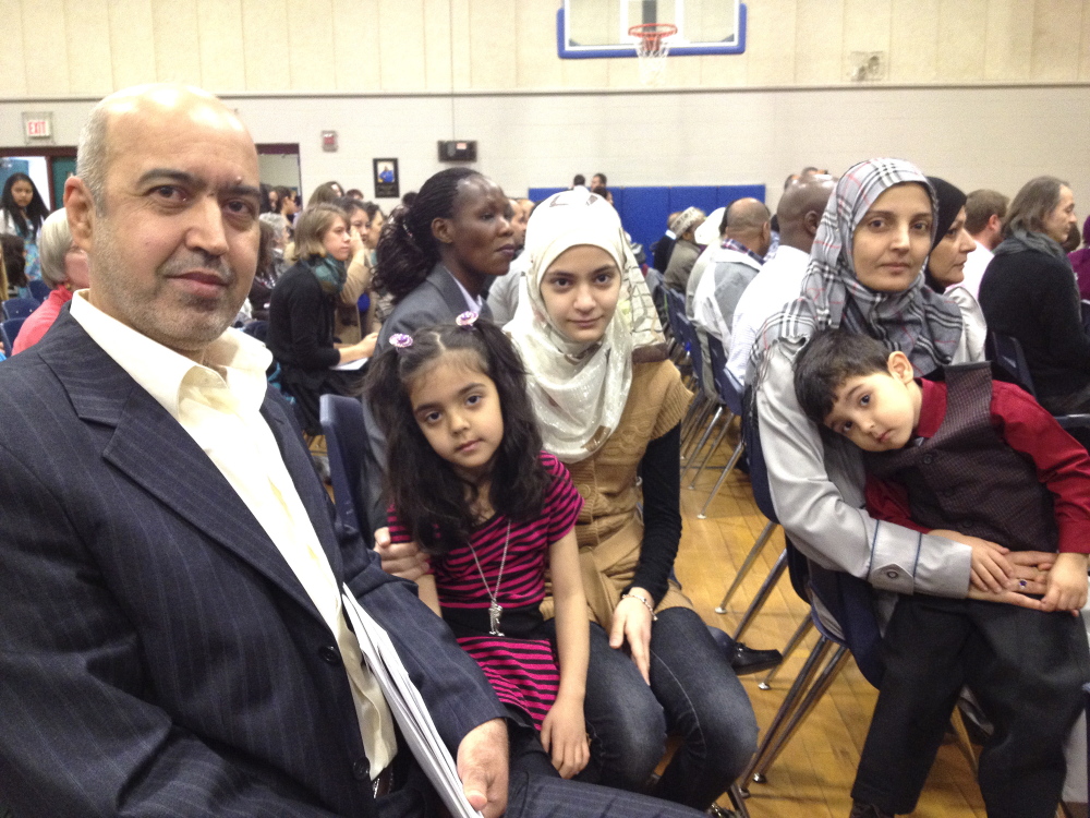 Kosay Alwan, left, came to the United States as a refugee from Iraq five years ago to escape the violence there and applied for his family to become citizens after realizing how safe the United States is. He was naturalized Friday at a ceremony at Lyman Moore Middle School in Portland along with his daughters, 6-year-old Naba and 13-year-old Sahar, and his wife Kawaid. His son, 3-year-old Ali, was born here and is already a citizen.