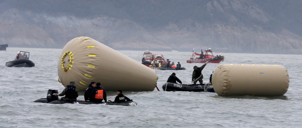 South Korean navy personnel try to install buoys to mark the sunken passenger ship Sewol in the water off the southern coast near Jindo, South Korea, Friday.