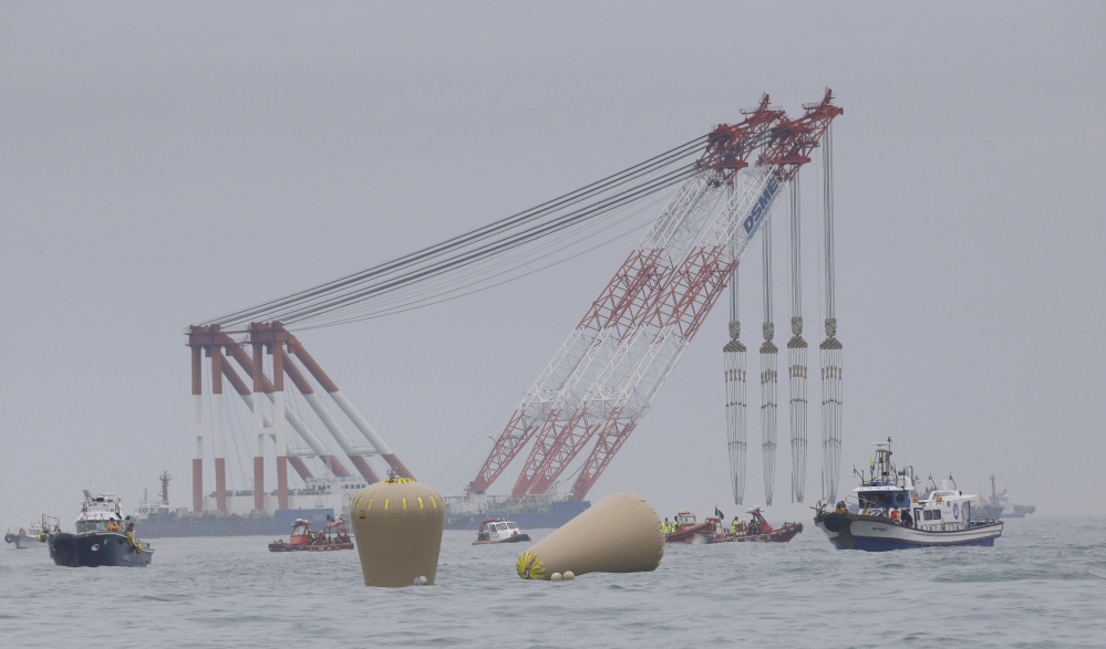 Cranes wait near the buoys installed to mark the sunken 6,852-ton ferry Sewol as fresh questions emerge about whether quicker action by the captain of the doomed ship could have saved lives.