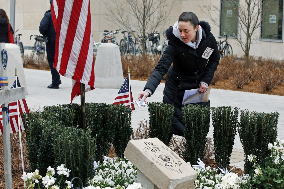 Massachusetts Institute of Technology employee Jennifer Earls places a folded paper crane near a memorial Friday for MIT Officer Sean Collier in Cambridge, Mass.