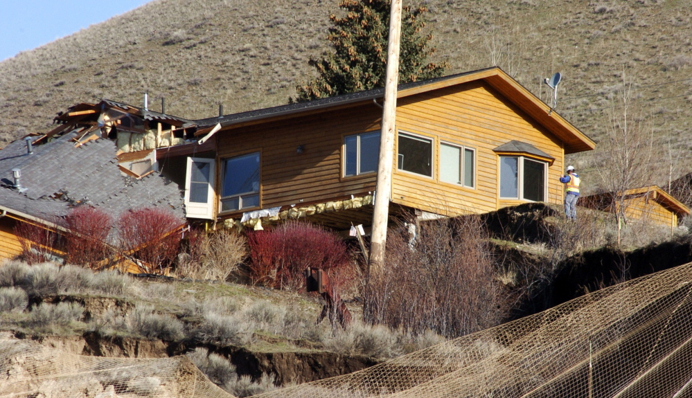 A worker inspects damage to a house at the top of a slow-motion landslide in Jackson, Wyo., on Saturday.