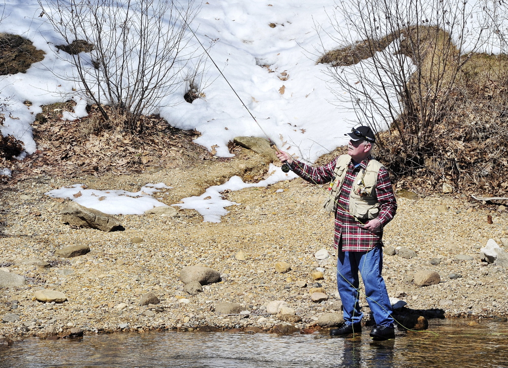With snow still on the ground behind him, Falmouth’s Bruce Wilson does what he’s done for the past 30 years – fishing on opening day, this time at Songo Locks in Naples.