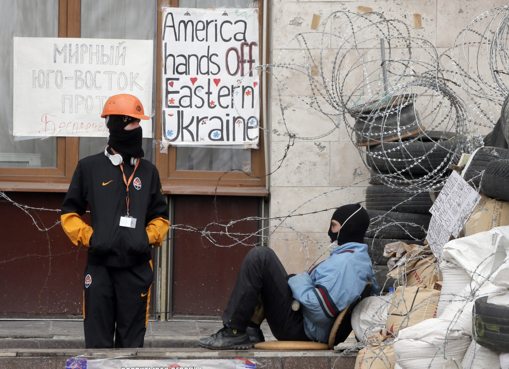 Masked pro-Russian insurgents guard a barricade Saturday at a building they had seized in Donetsk, Ukraine. Militants want the acting pro-Western government to resign.