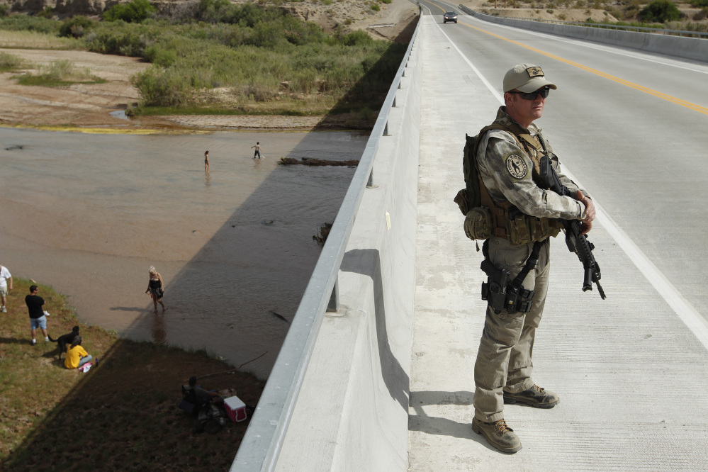 Justin Giles of Wasilla, Alaska, stands guard on a bridge over the Virgin River during a rally in support of Cliven Bundy near Bunkerville, Nev., on Friday.