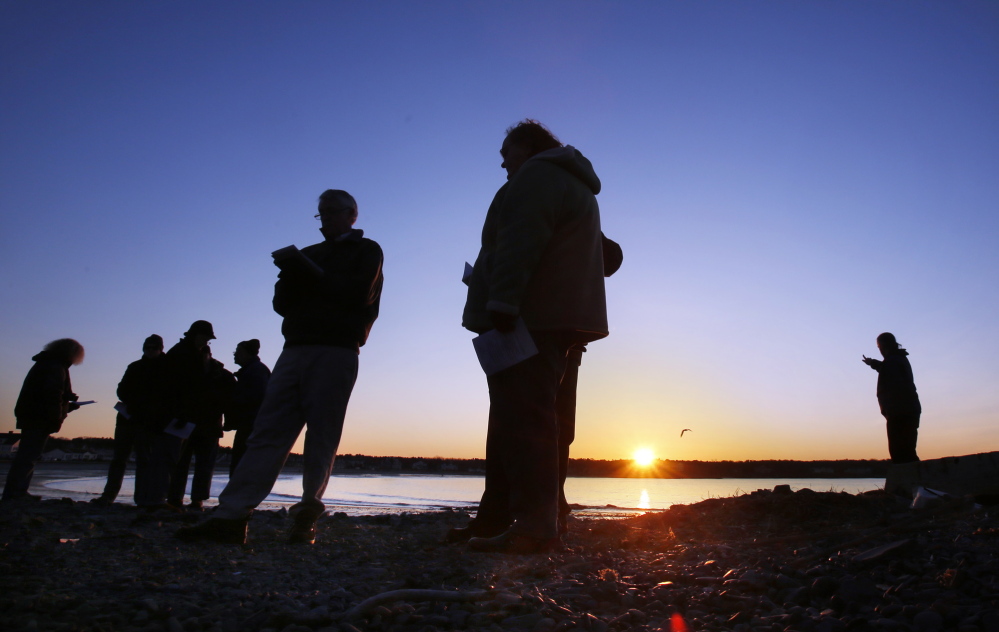 The Rev. Charles Whiston, fifth from left, of the South Congregational Church in Kennebunkport, recites a prayer during an ecumenical Easter sunrise service at Kennebunk Beach on Sunday.