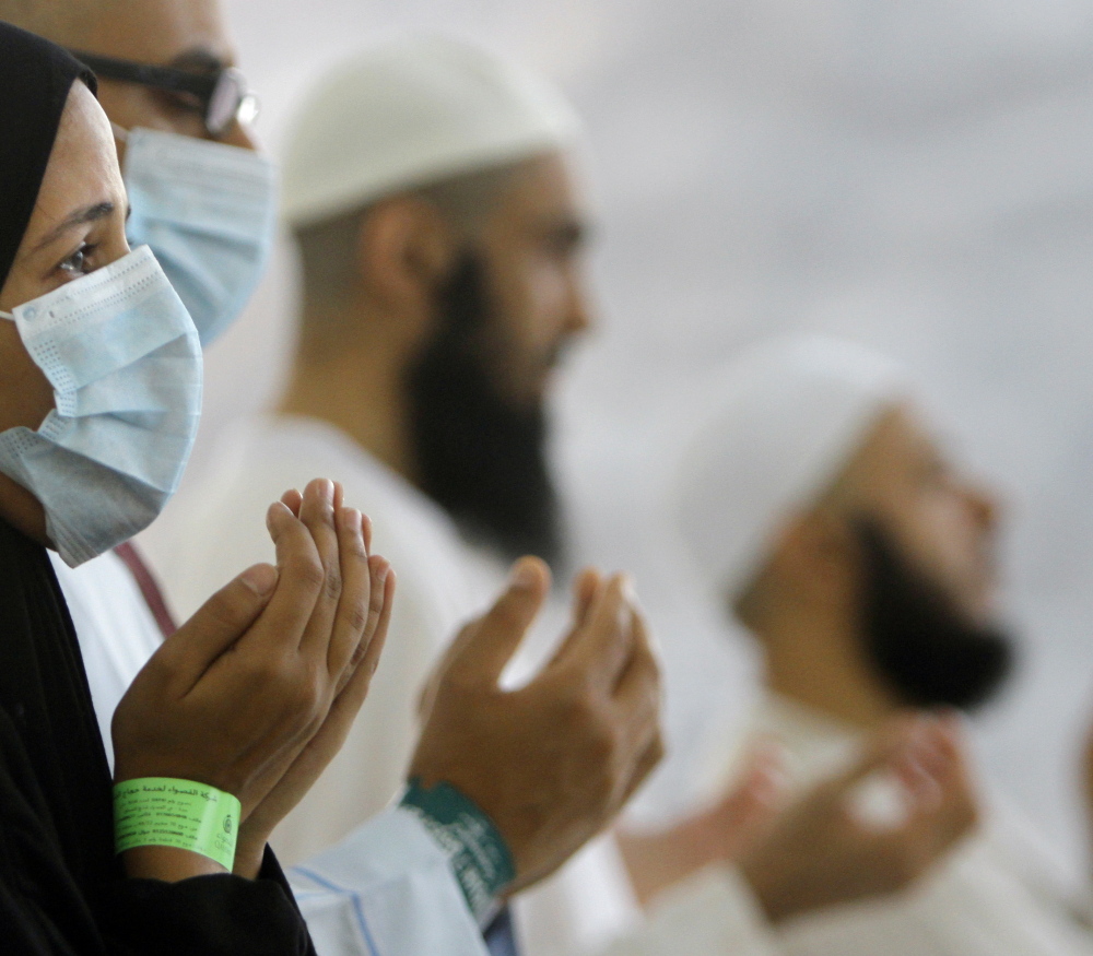 Muslim pilgrims, some wearing masks, pray near Mecca in Saudi Arabia in 2013.