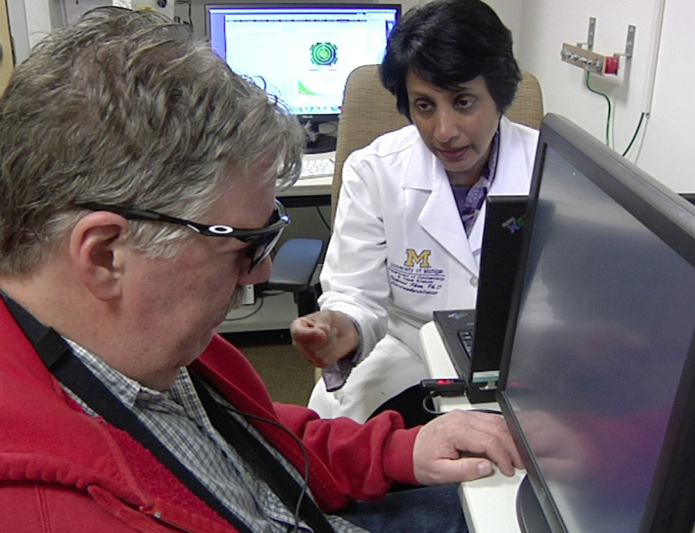 Dr. Naheed Khan, right, works with Roger Pontz, left, on an exercise to test how well he sees shapes on a computer screen at the University of Michigan Kellogg Eye Center, in Ann Arbor.