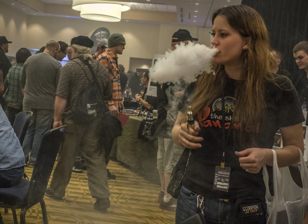 Anne Gilly of Long Island, N.Y., samples “Snickers” flavored vapor at a vendor’s booth at Vapefest. The gathering for enthusiasts of e-cigarettes and vapor delivery systems was held in Herndon, Va., in March.