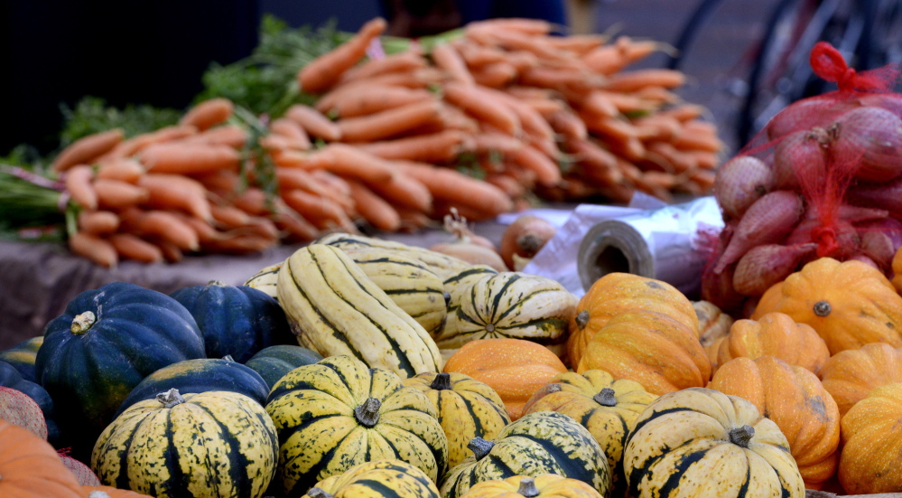 Local foods, like the carrots and squash displayed at the Portland Farmers’ Market last fall, could appear on more school lunch menus if legislators override Gov. LePage’s veto of a proposal that would let small growers more easily reach buyers like school districts and supermarkets.
