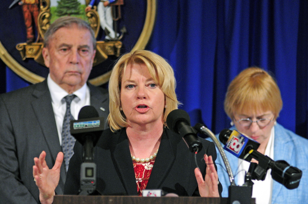 Assistant Attorney General Lisa Marchese, center, speaks during a news conference announcing release of the 10th report of the Domestic Abuse Homicide Review Panel on Thursday in the State House Hall of Flags in Augusta. She is flanked by Department of Public Safety Commissioner John Morris, left, and Attorney General Janet Mills, who also spoke at the event.