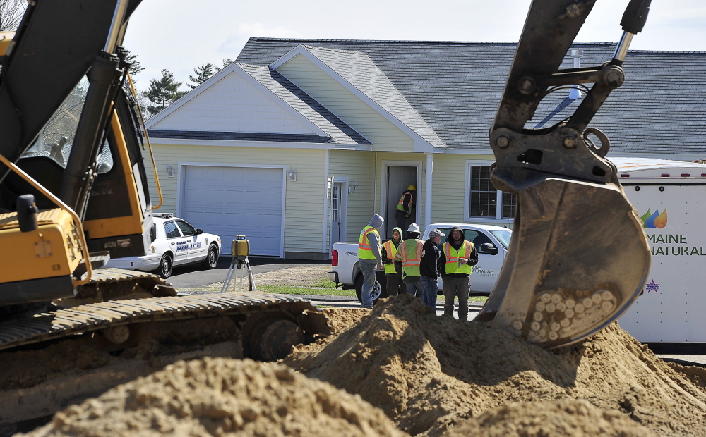Maine Natural Gas employees discuss the accident with construction workers as others go door to door evacuating residents and checking empty houses for gas levels after a gas main break caused by this excavator happened at Hawkes Farm development on Tink Drive in Gorham.
