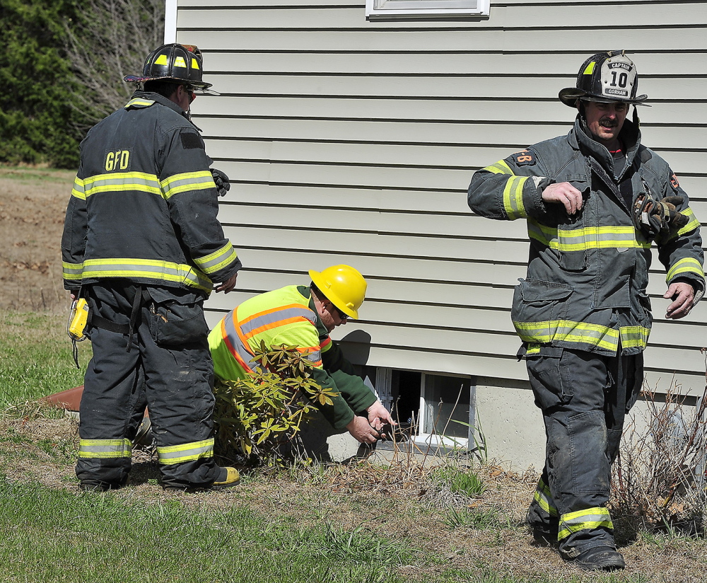 With help from Gorham firefighters Jason Baker, left, and Terry Deering, Maine Natural Gas technician Ron Dube checks for gas levels in this unoccupied home after a gas main was ruptured at Hawkes Farm development in Gorham.
